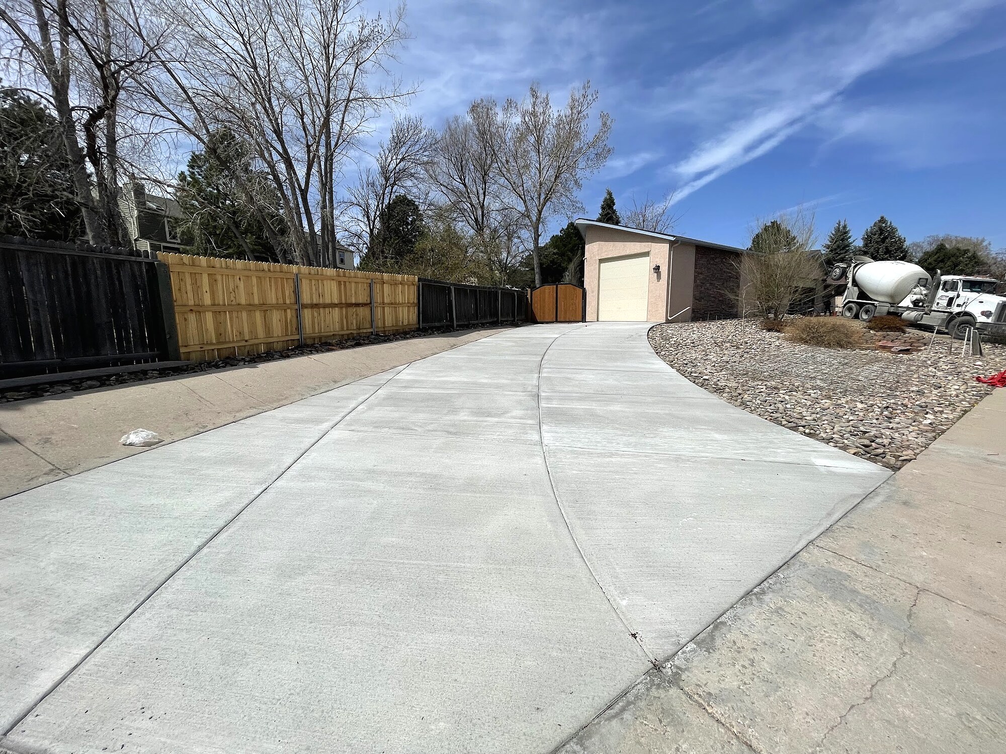 Wide pale concrete driveway leading to a detached garage in Colorado Springs.