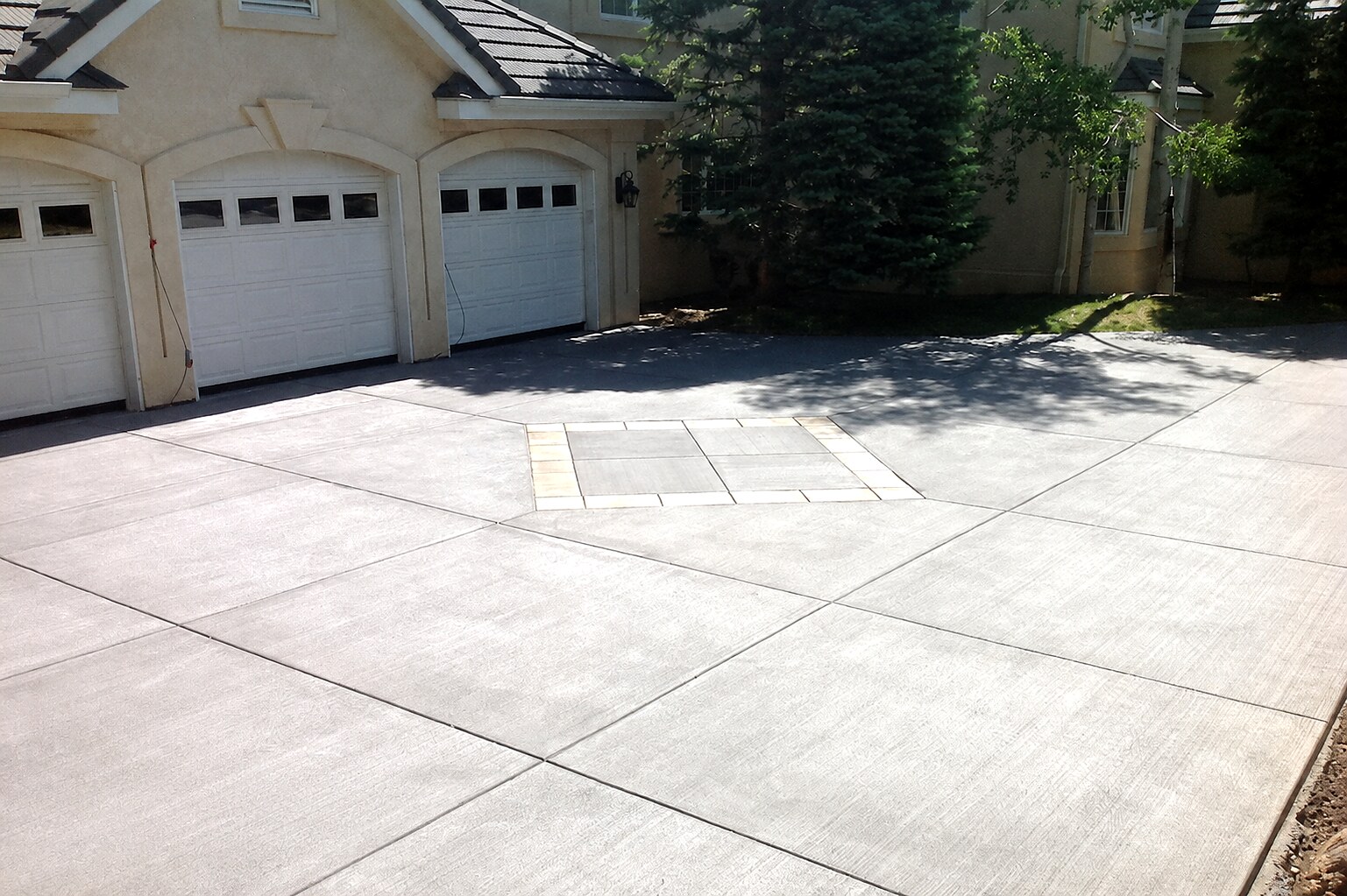 Large concrete driveway with a square decorative inset at an upscale home in Colorado Springs.
