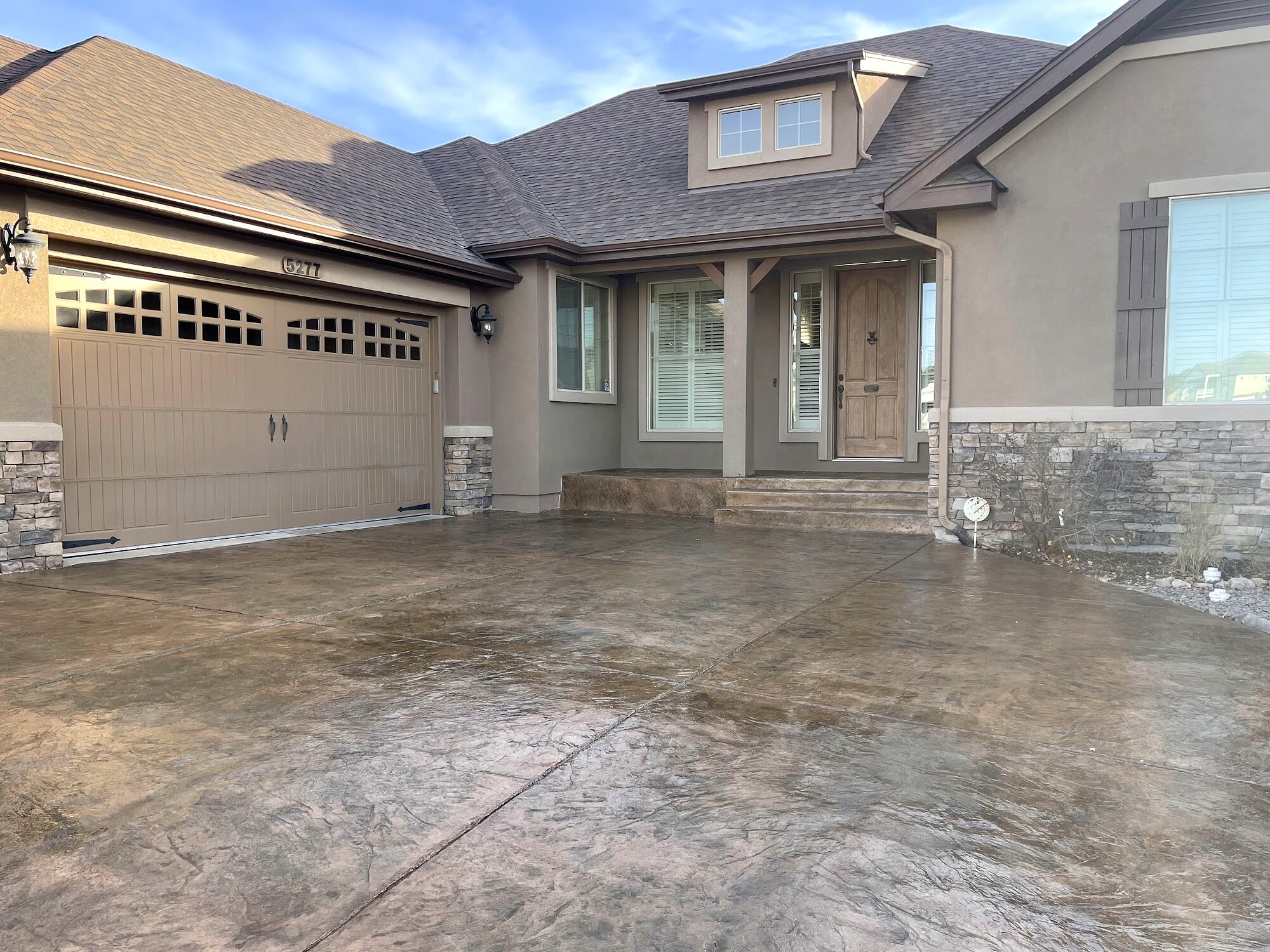 Gray stamped concrete driveway beside a stone facade in Colorado Springs.