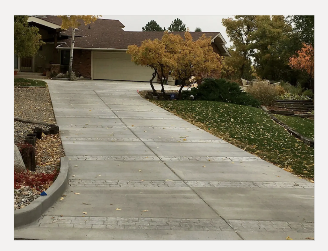 Broad concrete estate driveway framed by autumn landscaping in Colorado Springs.
