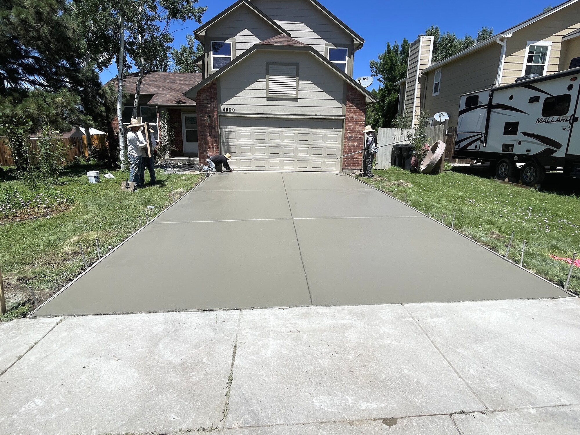 Smooth gray concrete driveway replacement at a two-story home in Colorado Springs.