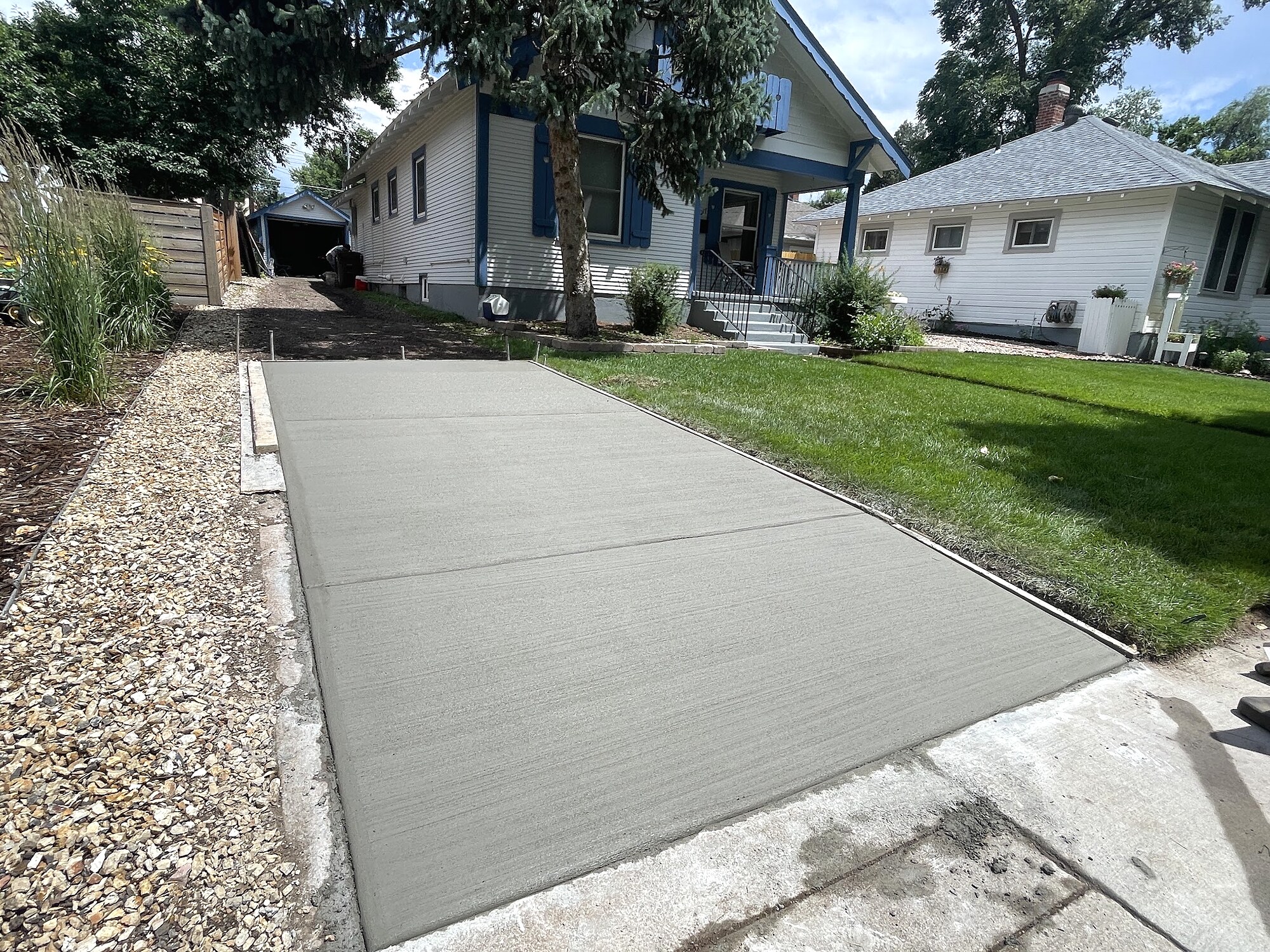 New concrete driveway at a white cottage-style home in Colorado Springs.
