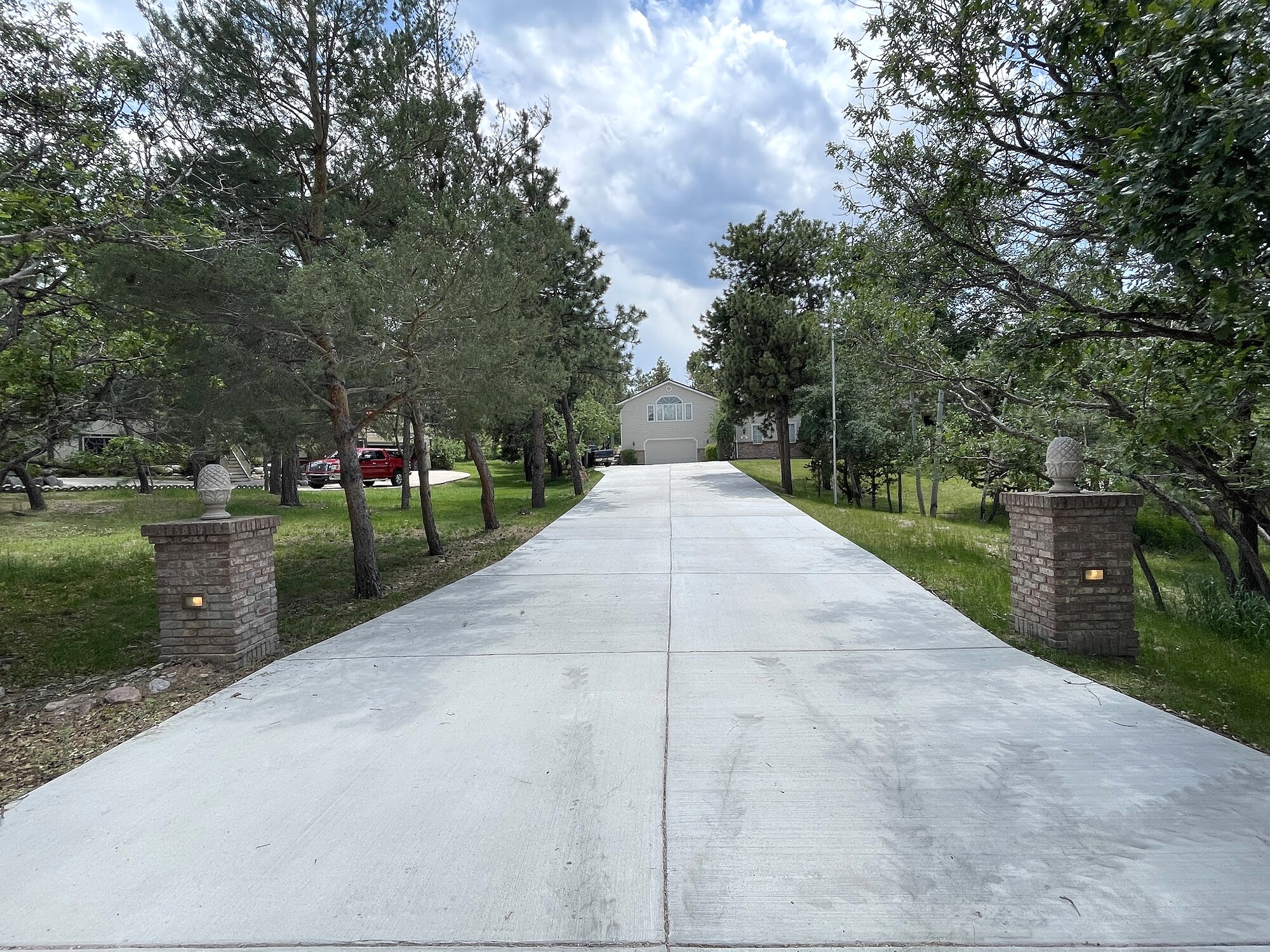 Long light concrete driveway at a gated wooded property in Colorado Springs.