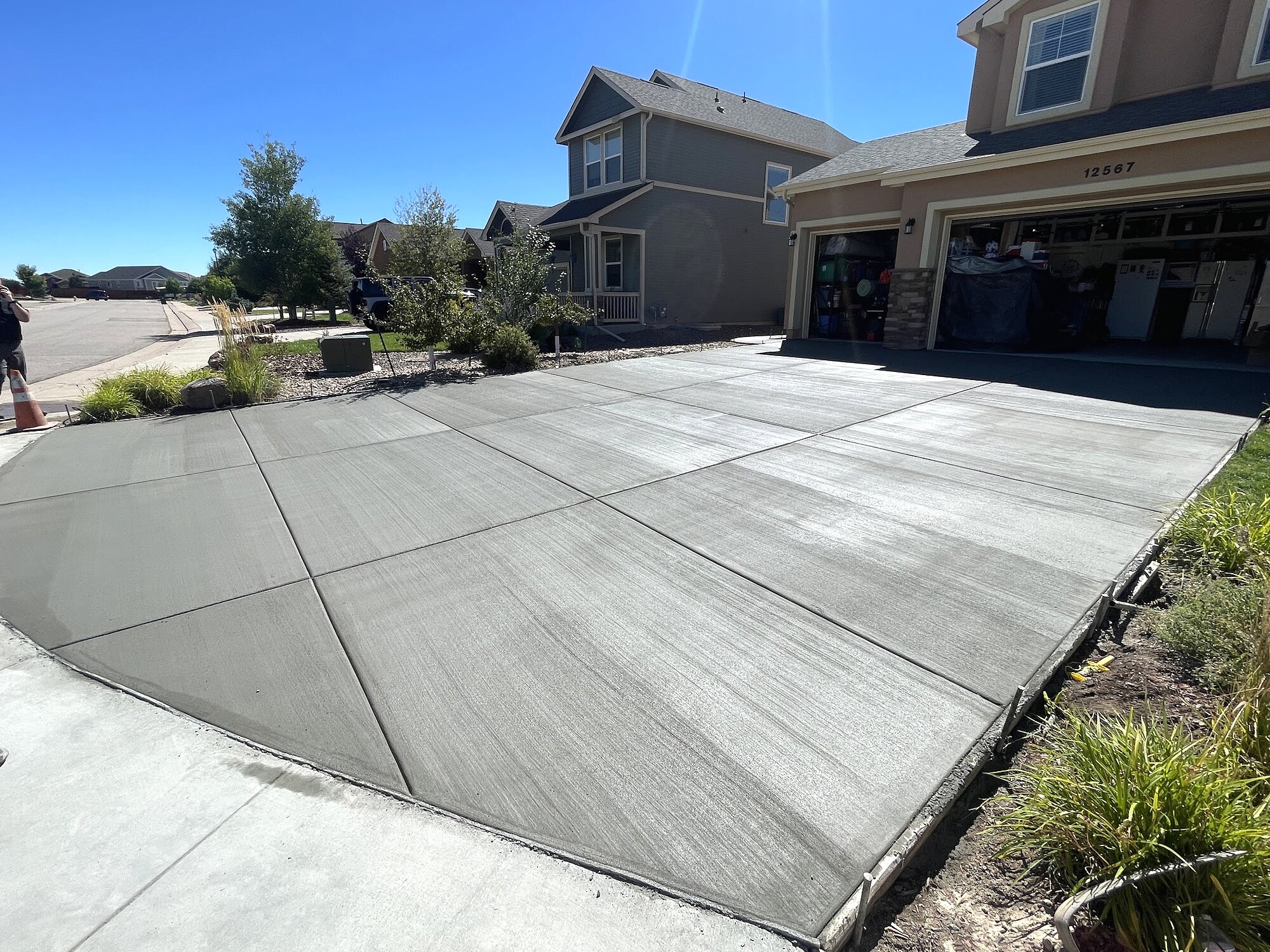 Fresh gray concrete driveway with a curved residential apron in Colorado Springs.